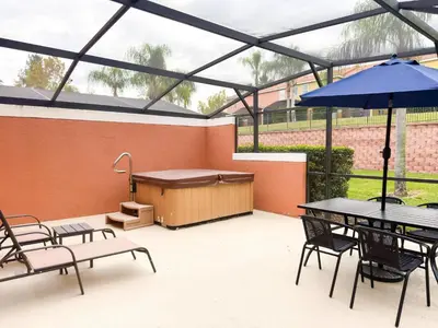 a patio with a table and chairs and an umbrella at ER3047WOR - Cozy 3BD Townhome w/ Private Hot Tub in Kissimmee