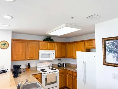 a kitchen with wooden cabinets and a white refrigerator at BHBR207 - Condo Close to Disney - 1 mile in Orlando
