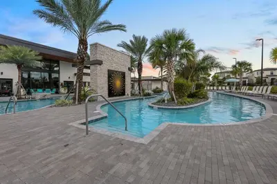 a swimming pool with palm trees in front of a building at Paradiso Grande 5Q c Piscina e Quartos Temáticos in Orlando