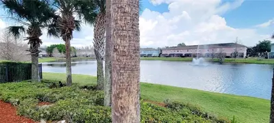 a view of a lake with palm trees and a building at Coral Cay Resort Your home away from home! in Kissimmee