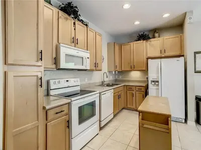 a kitchen with white appliances and wooden cabinets at Coral Cay Resort Your home away from home! in Kissimmee
