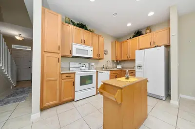 a kitchen with wooden cabinets and a white refrigerator at Coral Cay Resort Your home away from home! in Kissimmee