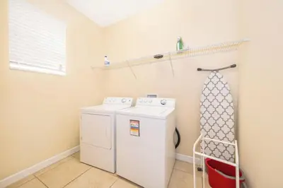 a laundry room with a washing machine and a shelf at Florida Dreaming home in Kissimmee