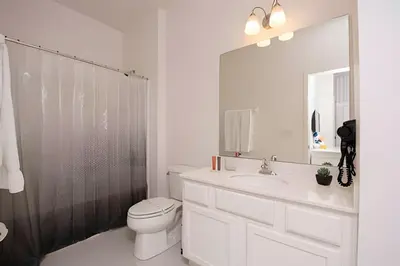 a bathroom with a toilet and a sink and a mirror at Casa c/ 9Q, piscina, spa e cinema! Perto da Disney in Kissimmee