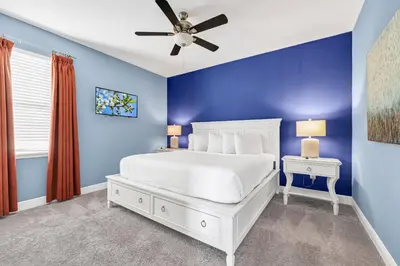 a blue bedroom with a white bed and a ceiling fan at Home With Private Pool, Theme & Game Room Near Disney With Resort & Waterpark Access - 7521Mr in Orlando