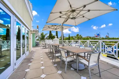 a patio with tables and chairs and an umbrella at Home With Private Pool, Theme & Game Room Near Disney With Resort & Waterpark Access - 7521Mr in Orlando