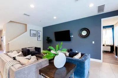 a living room with a couch and a tv on a blue wall at Incredible 8BR PetFriendly Encore Resort next to Disney - 7474 in Orlando