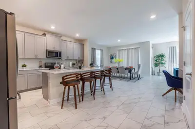 a kitchen with white cabinets and a table and chairs at Amazing 6BR at Storey Lake next to Disney - 2835 in Kissimmee