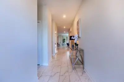 a hallway with white walls and a table with flowers on it at Amazing 6BR at Storey Lake next to Disney - 2835 in Kissimmee