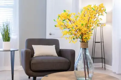 a vase with yellow flowers on a table next to a chair at Gorgeous 6BR at Storey Lake next to Disney - 2850 in Kissimmee