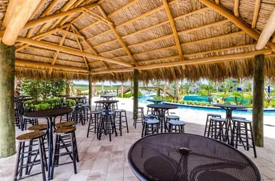 a restaurant with tables and chairs under a thatched roof at Stunning 6BR Lakeview at Storey Lake next to Disney - 2929 in Kissimmee