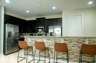 a kitchen with a counter with chairs and a refrigerator at Gorgeous 8BR PetFriendly at Encore Resort next to Disney - 7625 in Orlando
