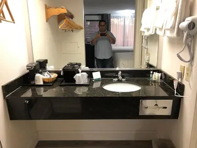 a man taking a picture of a bathroom sink at Green Palms Extended Stay in Kissimmee