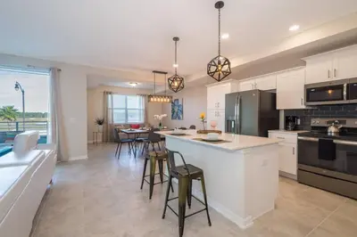 a kitchen with white cabinets and a island with bar stools at C4731-203-Storey Lake Resort Near Disney-Universal in Kissimmee
