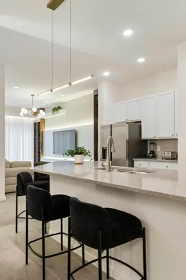 a kitchen with white cabinets and a counter with chairs at Orlando Paradise 5BR Themed Home in Orlando