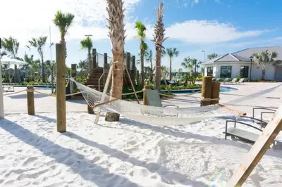 a hammock on a beach with palm trees at Casa 5Q c/ Piscina Privativa no Storey Lake in Kissimmee
