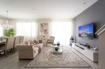 a living room with a couch and a tv on a wall at Casa 5Q c/ Piscina Privativa no Storey Lake in Kissimmee