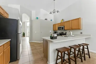 a kitchen with a black refrigerator and two bar stools at Vila 4Q com Piscina Privativa – Lake Berkley in Kissimmee