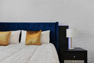 a bed with a blue headboard and a table with a lamp at Casa 9Q em Resort c/ Piscina – 11km da Disney in Kissimmee
