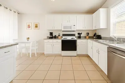 a white kitchen with white cabinets and a stove top oven at Casa 3 Quartos c/ Piscina perto da Disney! in Kissimmee