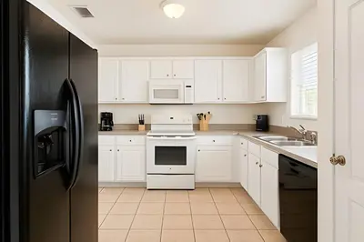 a kitchen with white cabinets and a black refrigerator at Casa 3 Quartos c/ Piscina perto da Disney! in Kissimmee