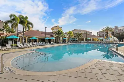 a large swimming pool at a resort with chairs and palm trees at Casa 3Q no Vista Cay- Perto da Universal in Orlando