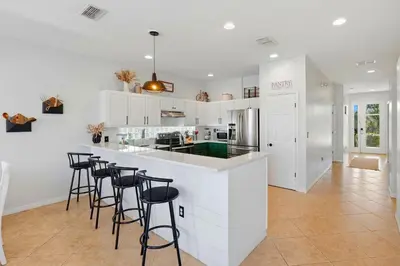 a kitchen with white cabinets and black bar stools at 2989 - Flamingo Farmhouse in Kissimmee