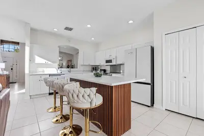 a kitchen with white cabinets and a bar with stools at Comfortable 6-Bedroom Getaway Near Top Attractions in Kissimmee