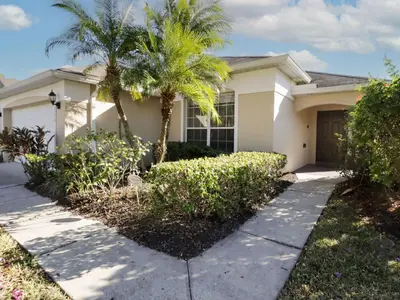 a white house with palm trees and a sidewalk at Holiday Home 4-Schlafzimmer-Ferienhaus mit Whirlpool by Interhome in Kissimmee