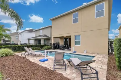 a patio with chairs and a pool in front of a house at Unforgettable 8-Bedroom Luxury Retreat in Orlando