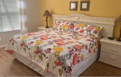 a bedroom with a bed with a floral bedspread at 648 - Spacious 6-Bedroom Emerald Island Retreat with Pool, Spa & Games Room Near Disney in Kissimmee