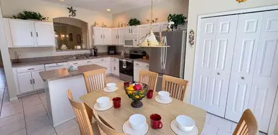 a kitchen with a table and chairs and a kitchen with white cabinets at 648 - Spacious 6-Bedroom Emerald Island Retreat with Pool, Spa & Games Room Near Disney in Kissimmee