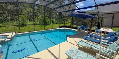 a large swimming pool with chairs and an umbrella at 648 - Spacious 6-Bedroom Emerald Island Retreat with Pool, Spa & Games Room Near Disney in Kissimmee