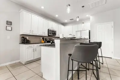a kitchen with white cabinets and bar stools at 4449 Shiva Loop in Kissimmee