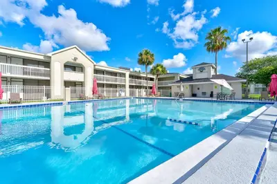 a swimming pool in front of a hotel with palm trees at Moana Adventure Suite Near Disney in Kissimmee