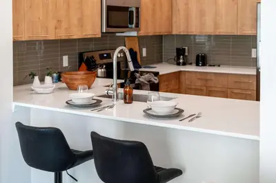 a kitchen with a counter with two cups and chairs at Riviere 2BR Apartment Pet Friendly Oasis Sleeps 6 Close to Epic Universe Pool & Gym in Orlando
