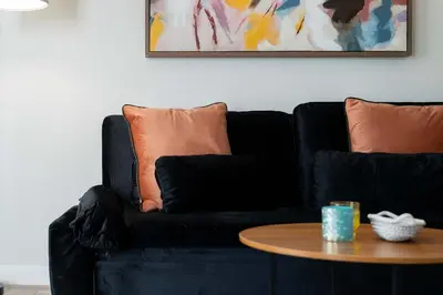 a black couch with orange pillows and a table at Riviere 2BR Apartment Pet Friendly Oasis Sleeps 6 Close to Epic Universe Pool & Gym in Orlando