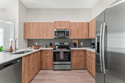 a kitchen with wooden cabinets and stainless steel appliances at Riviere 2BR Apartment Pet Friendly Oasis Sleeps 6 Close to Epic Universe Pool & Gym in Orlando
