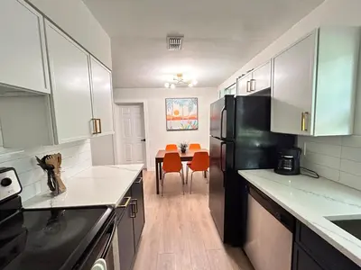 a kitchen with a black refrigerator and a table with orange chairs at Cozy Modern 3BR Escape - Sanford in Sanford