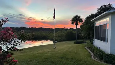 a flag pole in front of a house with a lake at The little Manatee Apartment in Orlando