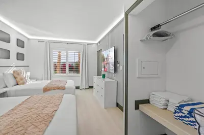 a white bedroom with two beds and a mirror at Cozy 1BR near Universal International Drive in Orlando