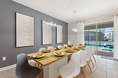 a dining room with a long table and white chairs at Bookmark Villa 8Q no Storey Lake c/ Piscina in Kissimmee