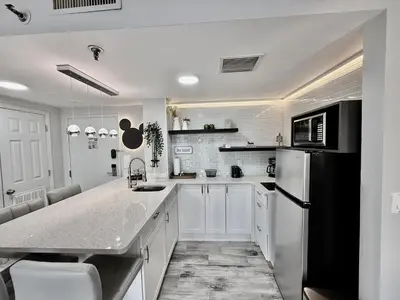 a kitchen with white cabinets and a black refrigerator at Entire condo near Universal Studios in Orlando - Free Resort Access in Orlando