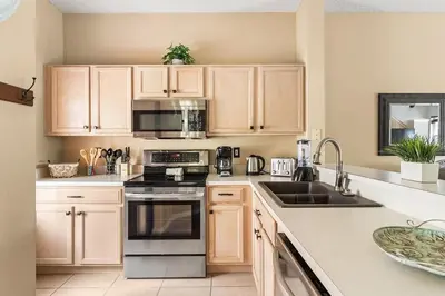 a kitchen with wooden cabinets and a stove top oven at Casa Familiar 3Q c/ Clubhouse Perto da Disney in Kissimmee