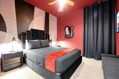 a bedroom with a large bed with red walls at Themed Villa with Private Pool, Game Room, Resort Amenities, BBQ in Orlando