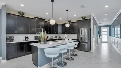 a kitchen with black cabinets and a island with bar stools at Pool & BBQ | Disney-Themed Cozy 6BD | Near Disney in Kissimmee