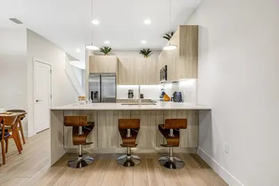 a kitchen with a counter and some chairs in a room at A Magical and Cozy Family Getaway 3BR Home Near Disney Studios in Orlando