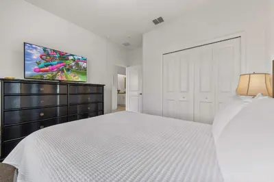 a white bedroom with a large bed and a dresser at South-Facing Pool 5BR Storey Lake Lazy River 2437 in Kissimmee