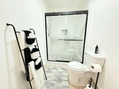 a white bathroom with a shower and a toilet at Family Pool Home |Close to Disney/Universal/Epic in Kissimmee