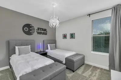 a bedroom with two beds and a couch and a chandelier at Classy 6BR Home with Private Pool in Kissimmee